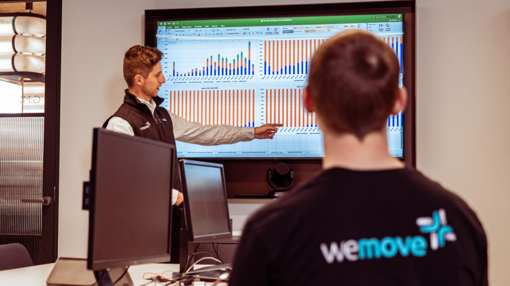 An image of a man pointing at a graph while another man looks on