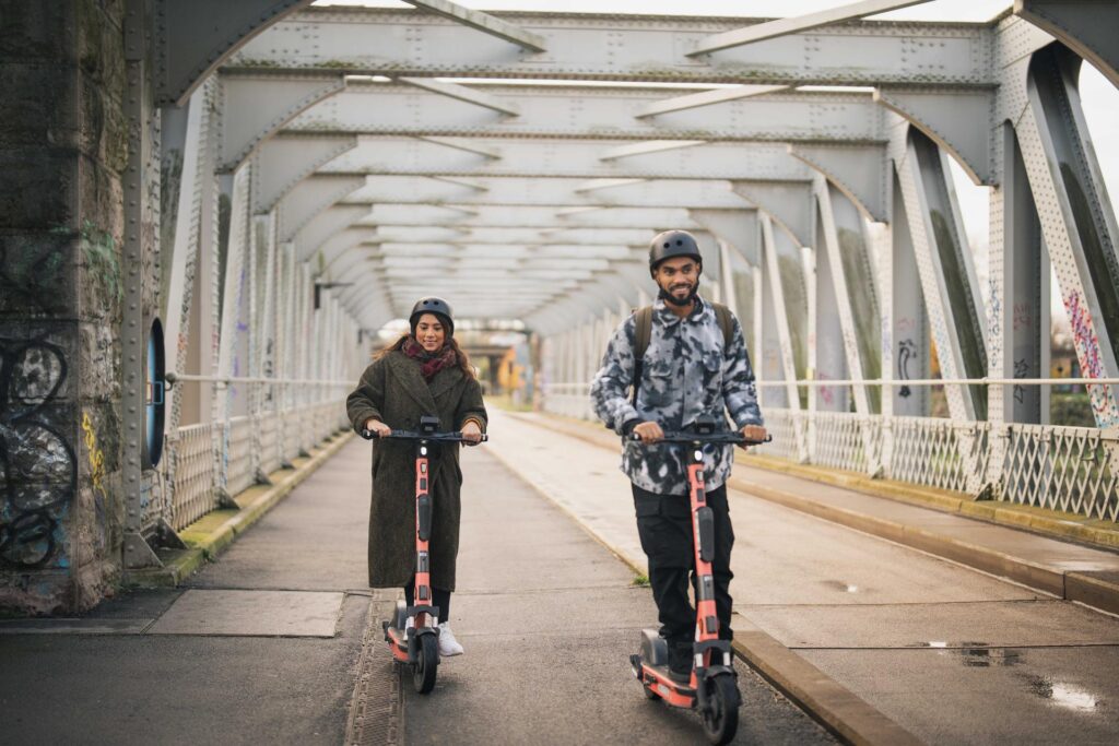 Two people on e-scooters riding on a segregated path in England