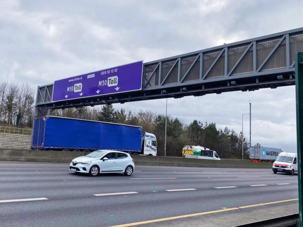 A sign for the M50 tolling station above a busy road
