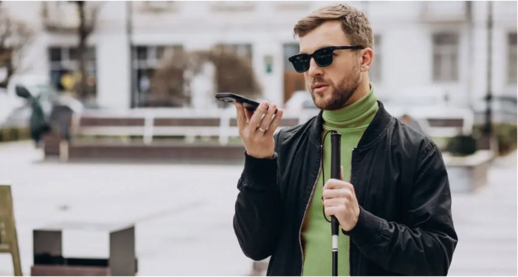 An image showing a blind man speaking to his mobile phone holding a cane