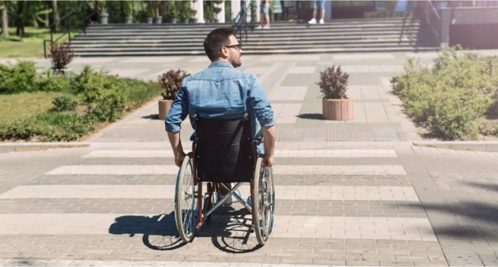 An image showing a man in a wheelchair crossing a road using a crossing point