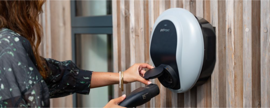 An image of a woman using one of Pod Point's EV wall charging units