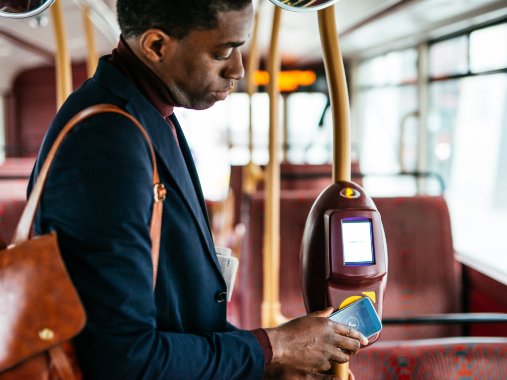 An image of a man paying for his bus fare with his phone