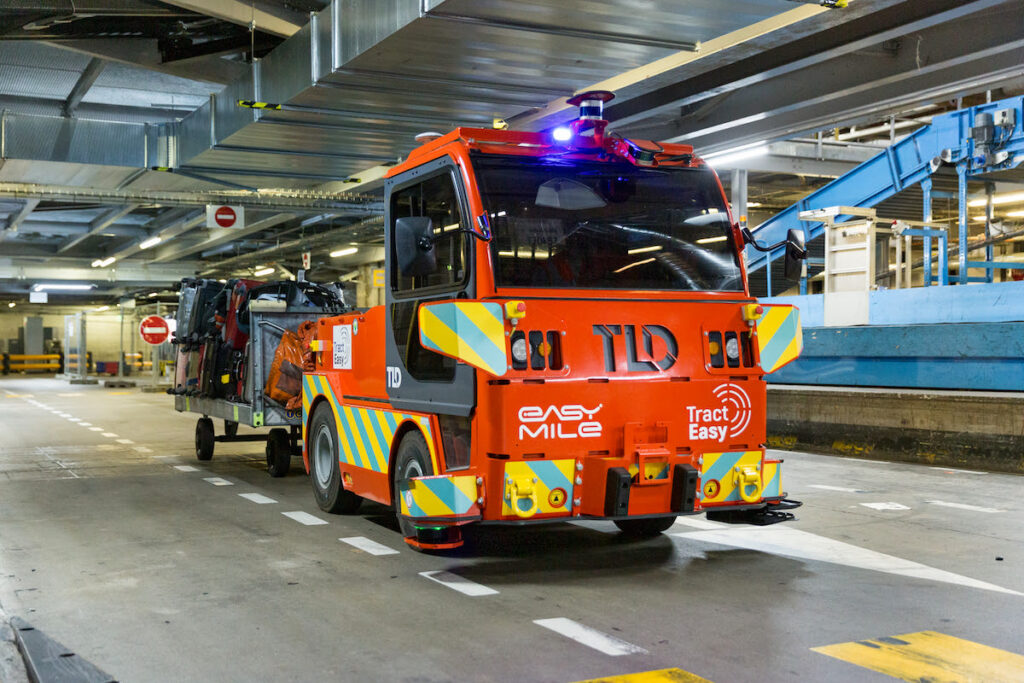 A red autonomous tow tractor in a depot