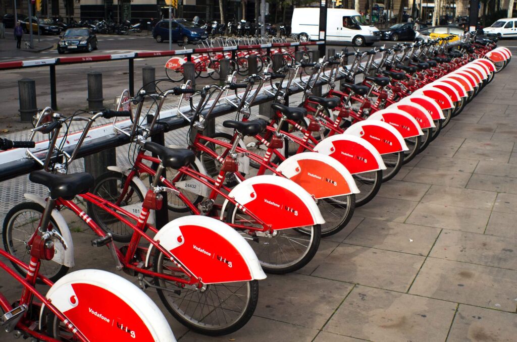 A line of red Vodafone e-bikes parked in a city