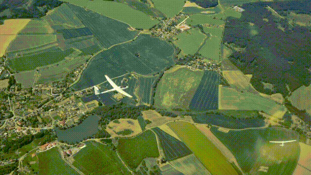 A glider flying over lush green fields