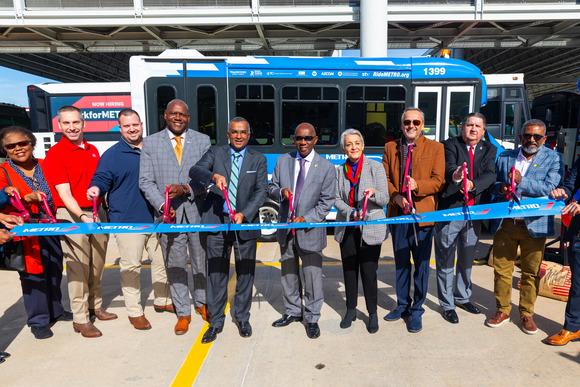 A group of METRO employees cut a ribbon in front of an autonomous shuttle alongside the mayor of houston