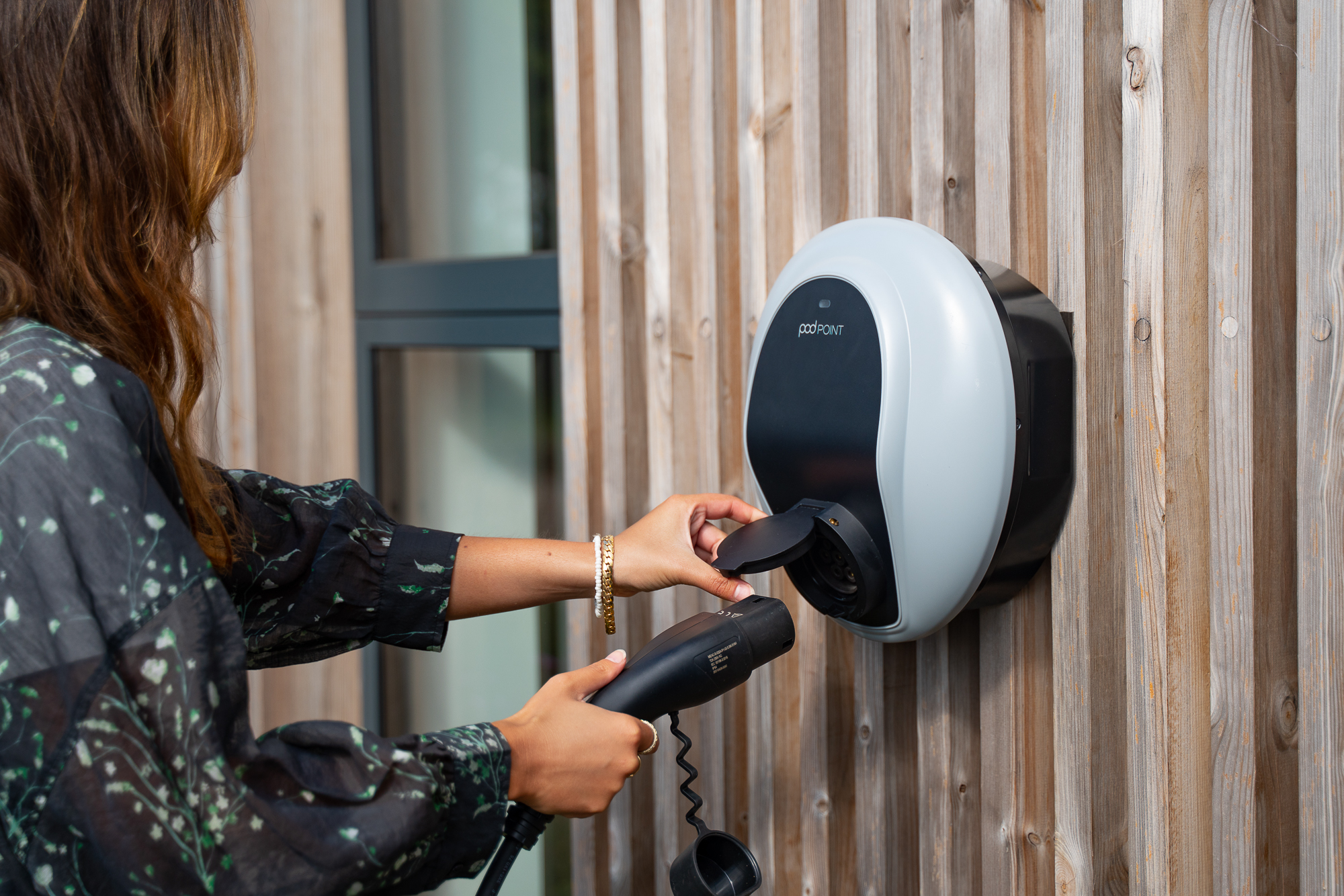 Woman using a wall-mounted electric vehicle charger