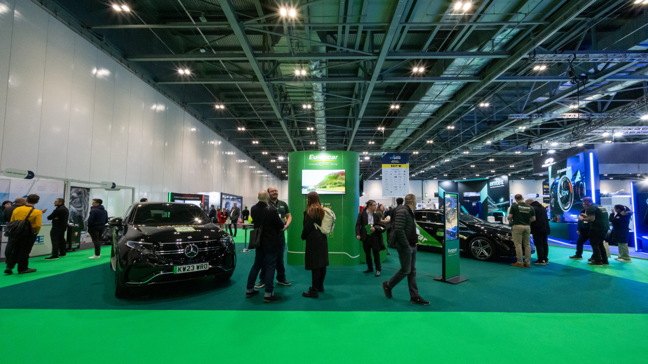 People standing at a car display at the London EV Show 2023