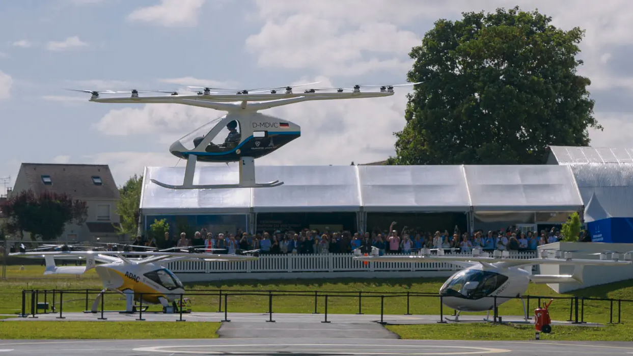 A crowd watching a test flight of an eVTOL aircraft