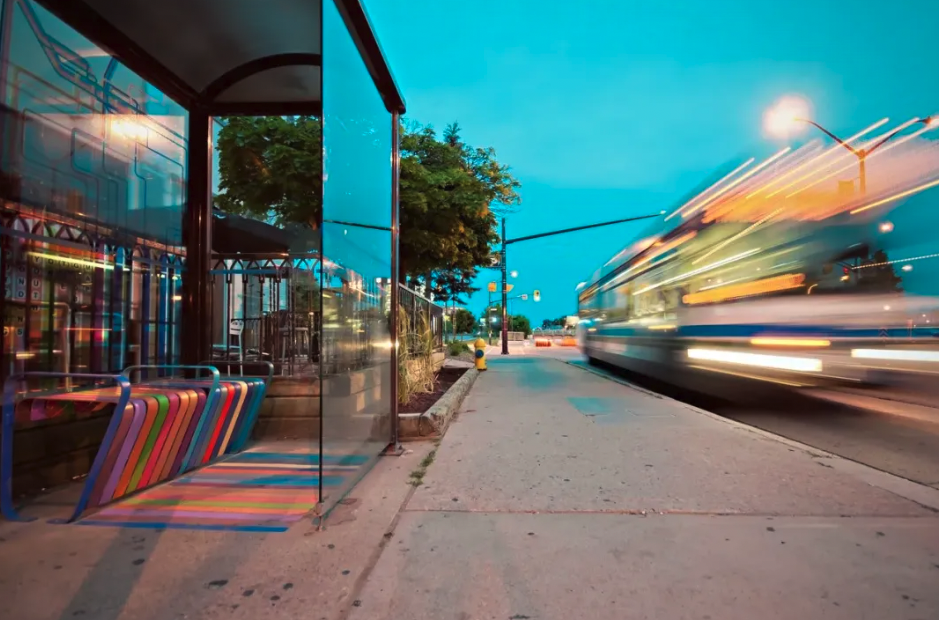 Image of a bus station, with a bus in motion travelling past