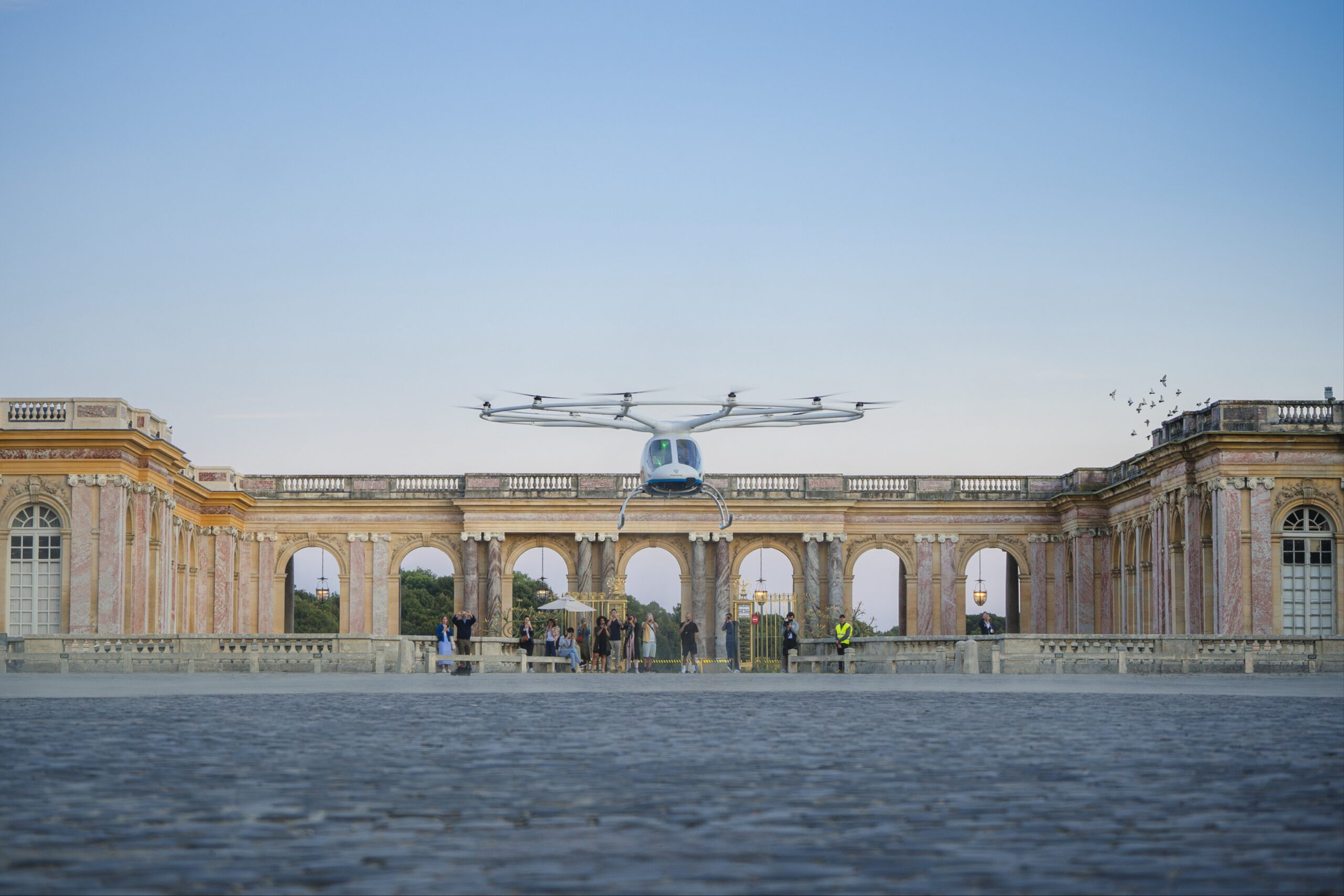 Volocopter aircraft taking off over a courtyard at the Palace of Versailles