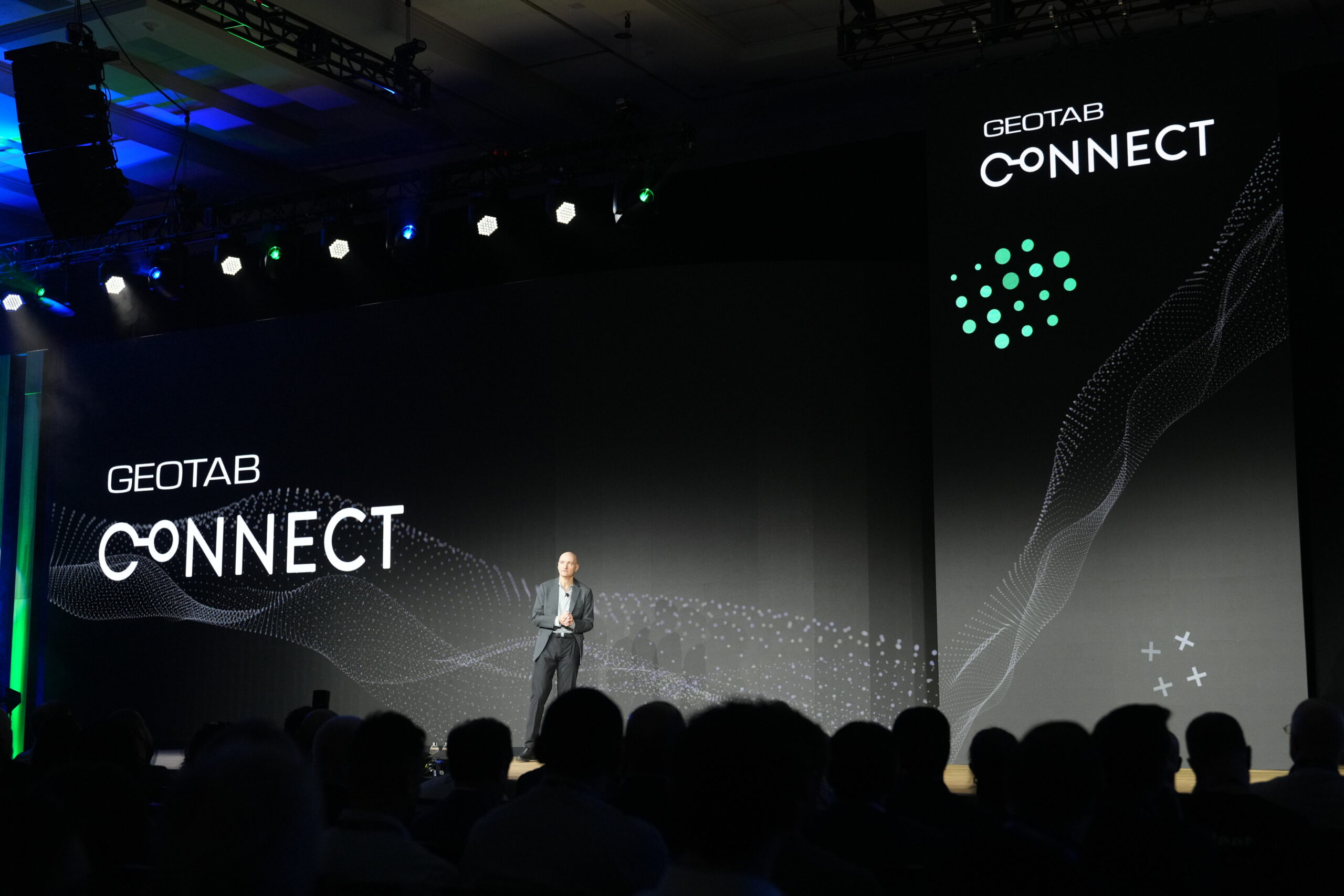 A man onstage at a conference, the background is black with white text "Geotab CONNECT"