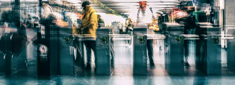 Blurred motion of commuters passing through subway turnstiles, symbolizing urban transit, public transportation, and fare evasion concerns