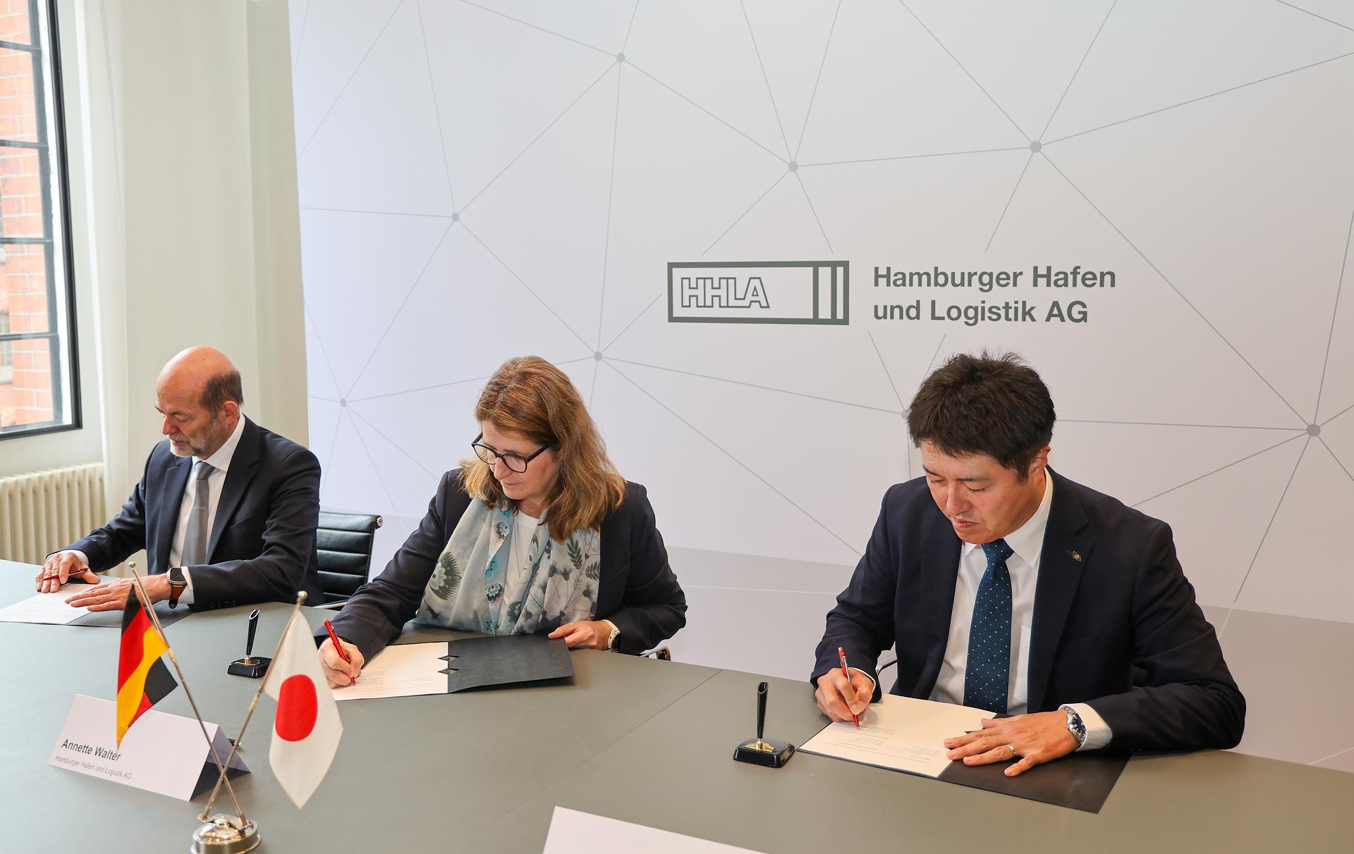 A set of three people signing contracts