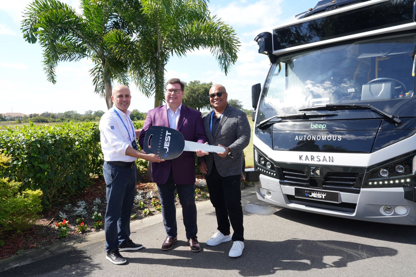 Three men stood by a Karsan bus