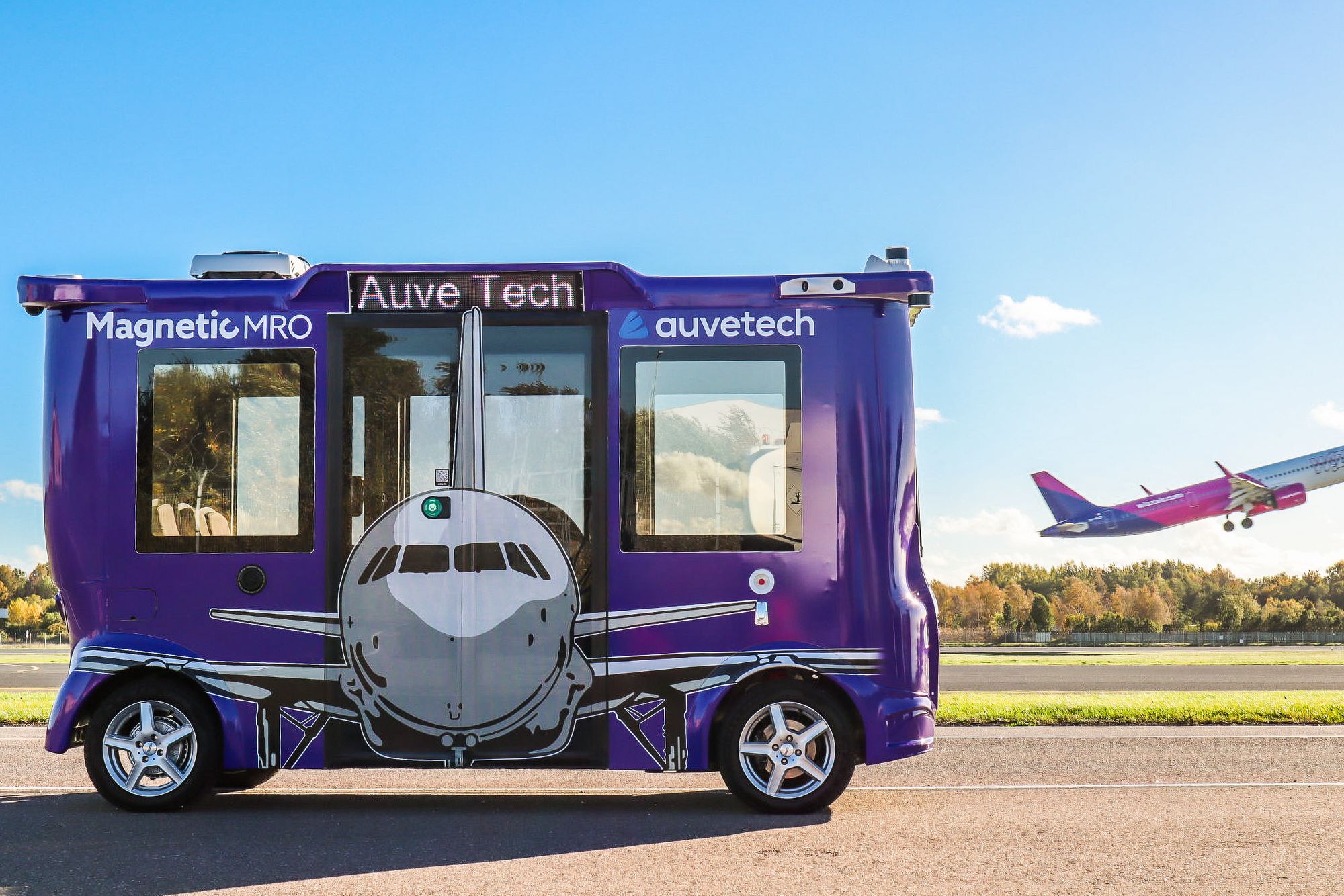 A purple autonomous shuttle with a plane image on the side 