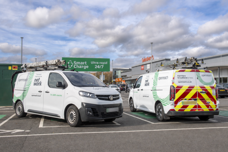 Two white electric Openreach vans with roof ladders parked at ultra-rapid EV charging bays in a retail car park