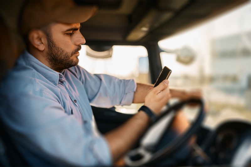 Truck driver using a mobile phone while driving, illustrating the risk of driver distraction